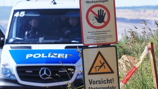 Polizeifahrzeug am Tagebau Garzweiler neben Warnschildern mit den Aufschriften "Werksanlagen".