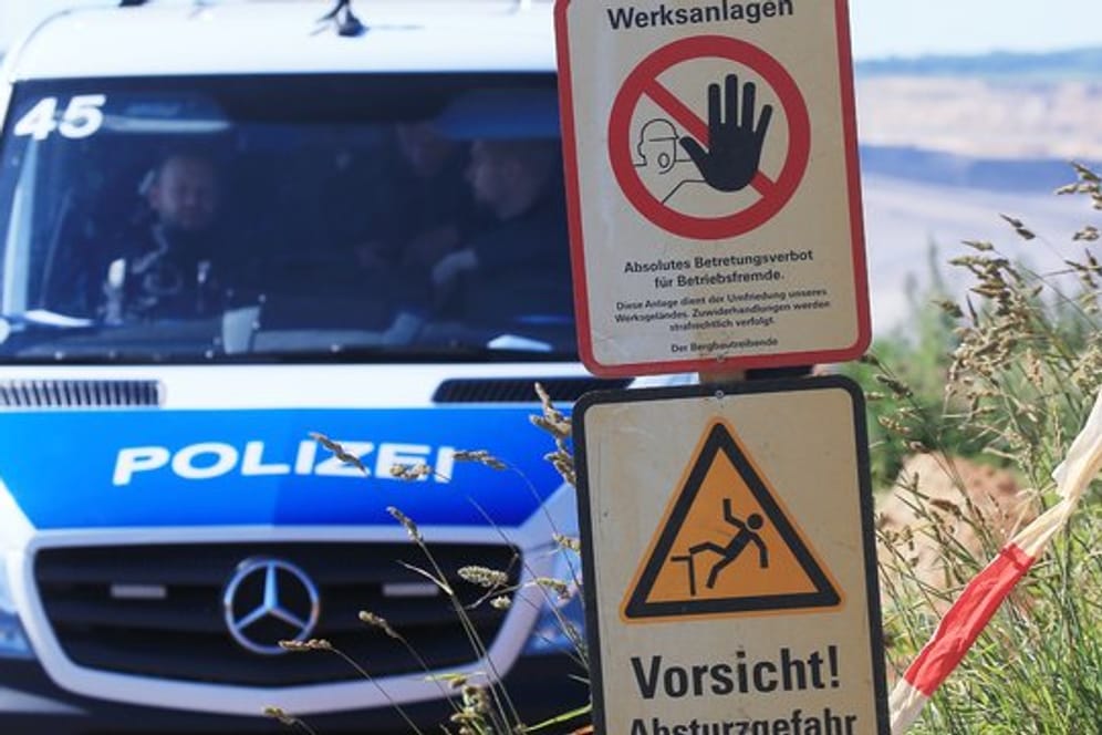 Polizeifahrzeug am Tagebau Garzweiler neben Warnschildern mit den Aufschriften "Werksanlagen".