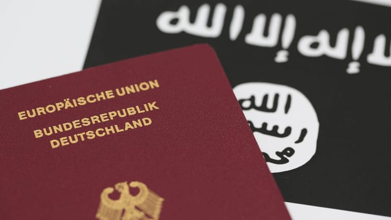 Ein deutscher Reisepass vor der Flagge des IS: Die Bundesregierung weiß offenbar nichts über den Verbleib von über 160 deutschen IS-Anhängern. (Symbolbild)