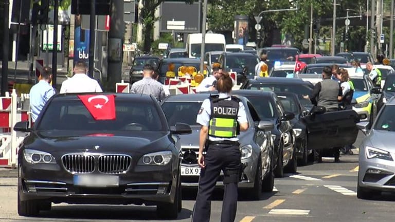Eine Polizistin steht vor den Fahrzeugen eines türkischen Hochzeutskorsos.