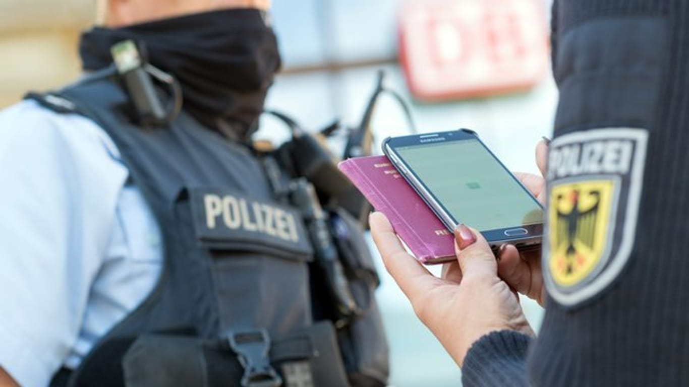 Eine Bundespolizistin scannt mit einem Mobiltelefon einen Reisepass.