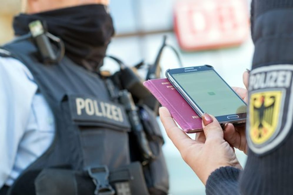 Eine Bundespolizistin scannt mit einem Mobiltelefon einen Reisepass.