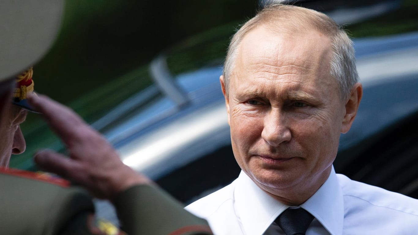 Wladimir Putin wird von einem Offizier bei einer Kranzniederlegung in Moskau begrüßt.