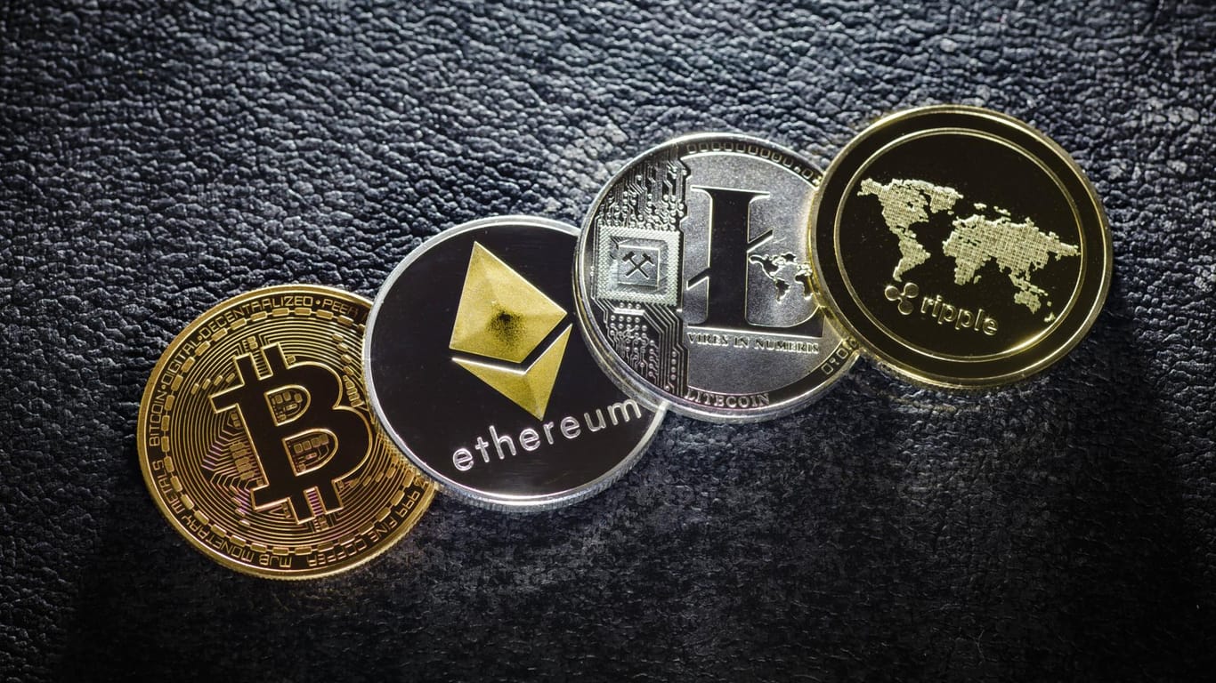 Münzen der Kryptowährungen Bitcoin, Ethereum, Litecoin und ripple liegen auf einem Tisch: Notenbanken halten eine weltweite Regulierung der Cyber-Devisen für erforderlich.