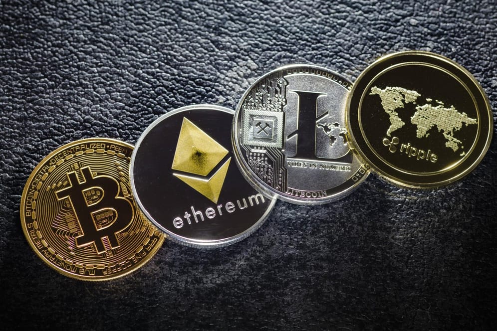 Münzen der Kryptowährungen Bitcoin, Ethereum, Litecoin und ripple liegen auf einem Tisch: Notenbanken halten eine weltweite Regulierung der Cyber-Devisen für erforderlich.
