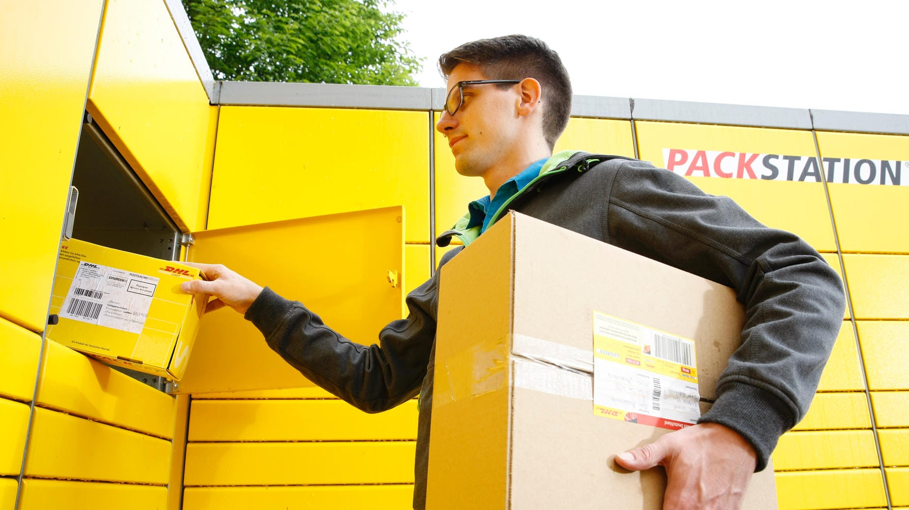 Mann legt Pakete in eine Poststation: Für Bücher- und Warensendung gelten ab Juli neue Maximalmaße.