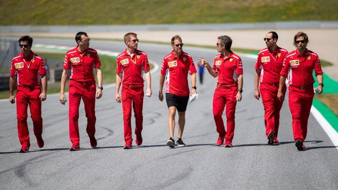Sebastian Vettel (M) geht mit seinem Team die Rennstrecke in Spielberg ab.