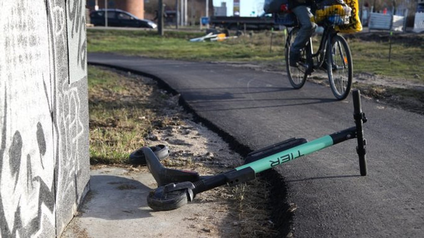 Ein Radfahrer weicht auf einem Radweg einem umgekippten E-Tretroller aus.