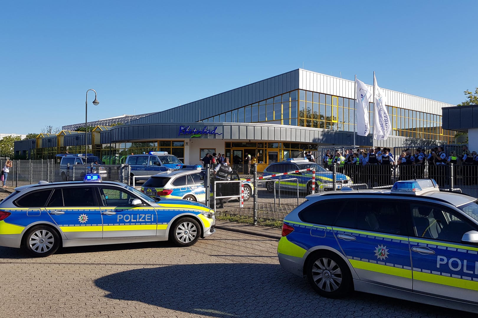 Düsseldorf: Zahlreiche Polizeifahrzeuge stehen am späten Nachmittag vor dem Rheinbad, wo es zu einem Streit mit mehreren Hundert beteiligten Badegästen gekommen ist.