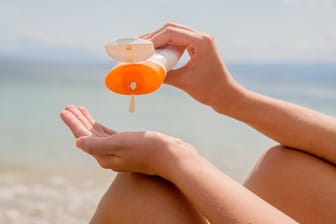 Frau benutzt Sonnencreme: In Sonnenschutzlotionen sind Substanzen enthalten, die der Tier- und Pflanzenwelt des Meeres schaden können.