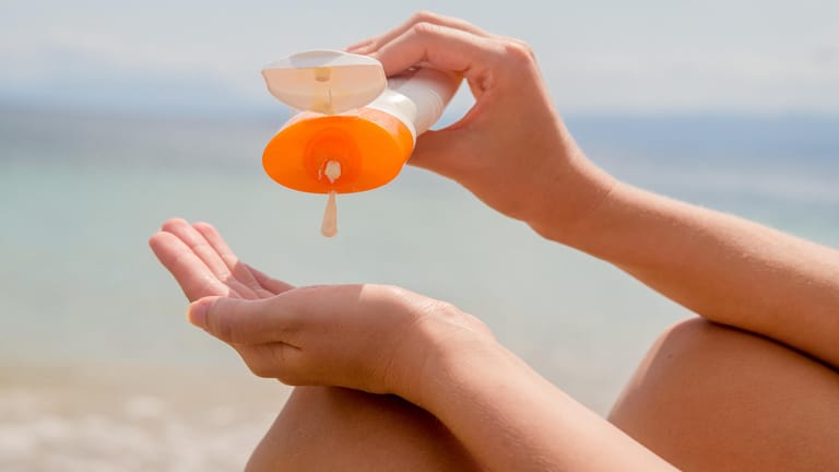 Frau benutzt Sonnencreme: In Sonnenschutzlotionen sind Substanzen enthalten, die der Tier- und Pflanzenwelt des Meeres schaden können.
