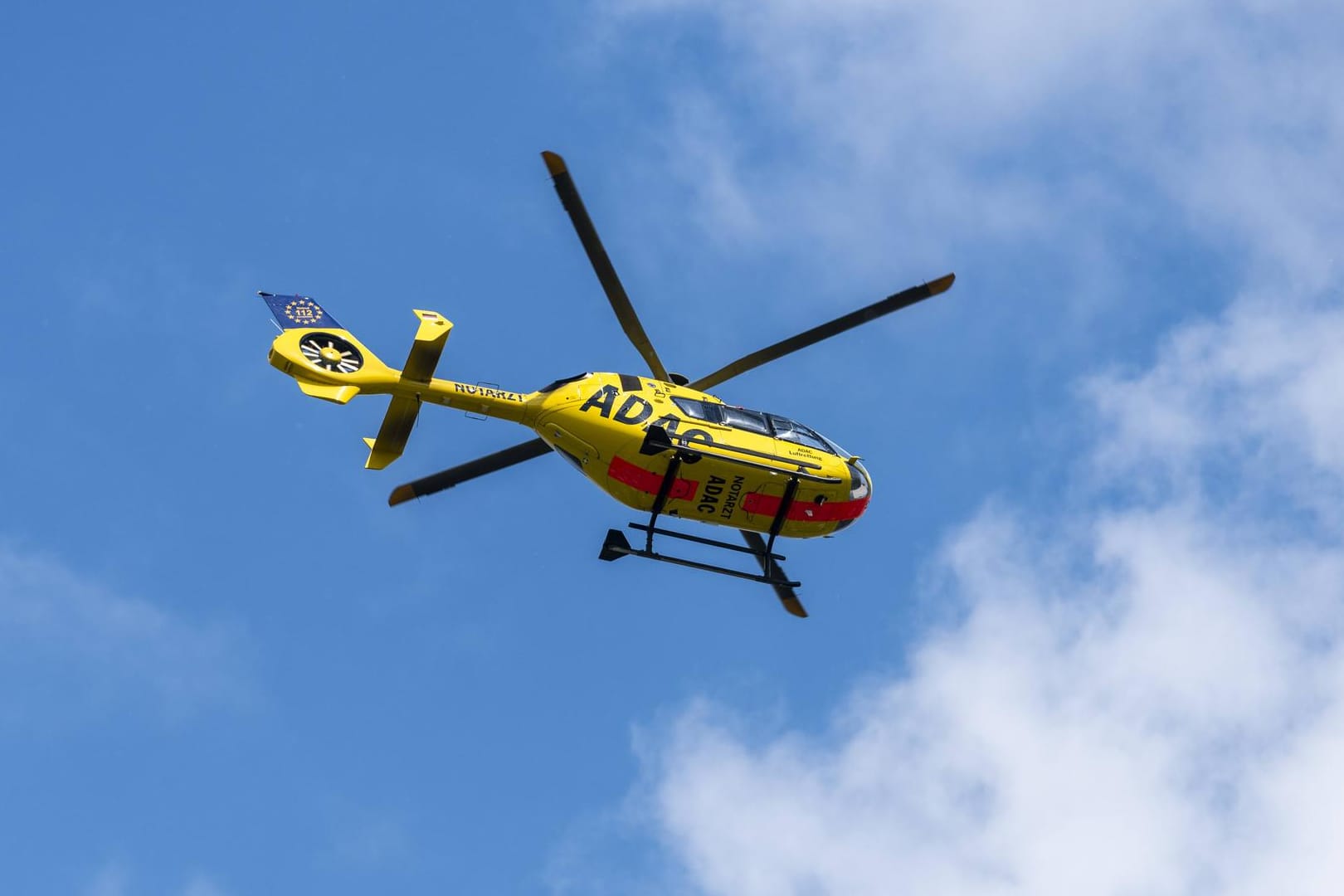 Ein Rettungshubschrauber des ADAC fliegt in der Luft: In Karlsruhe wurde ein Mann schwer verletzt.