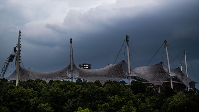 Bayern, München: Dunkle Wolken sind hinter dem Dach vom Olympiastadion zu sehen.