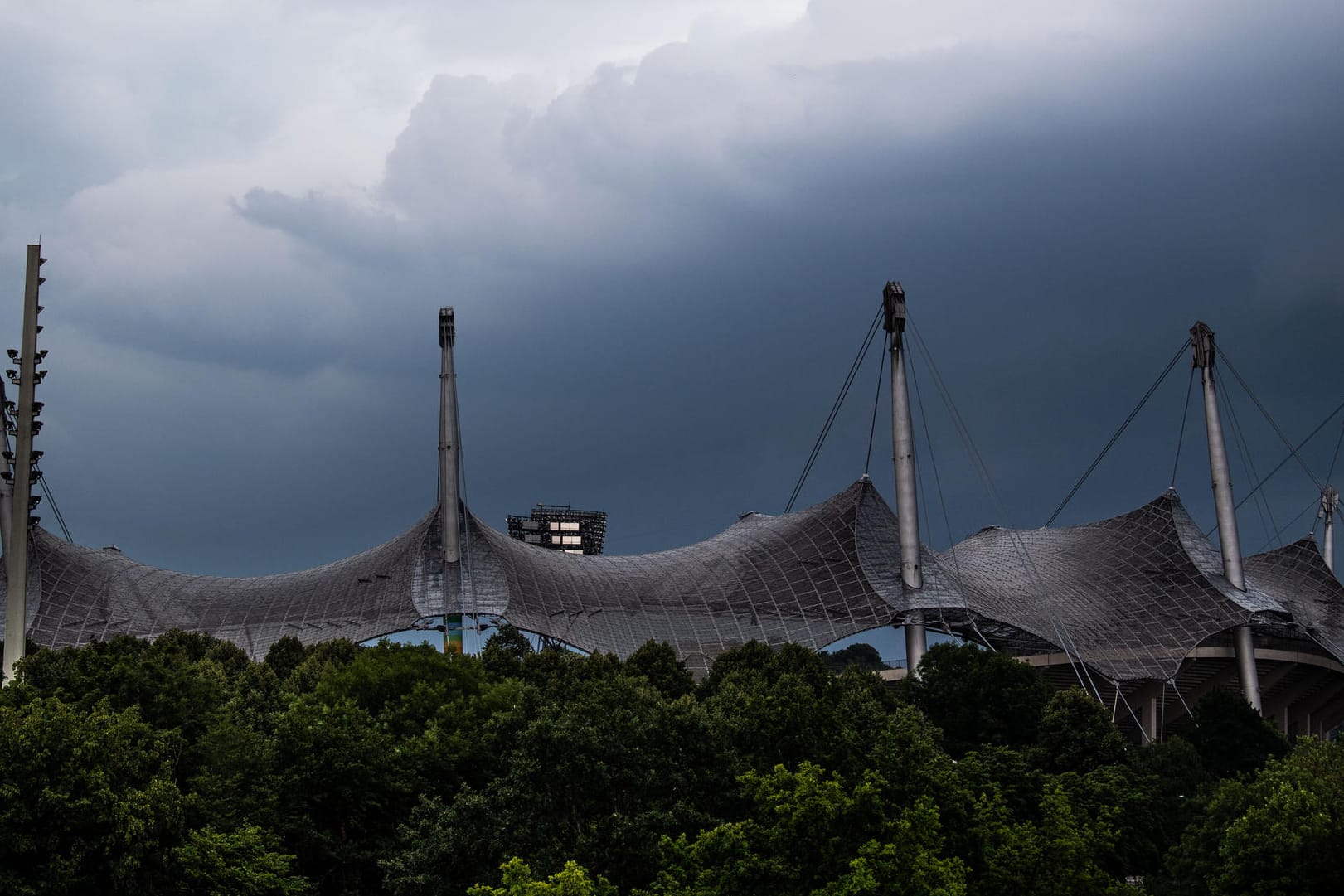 Bayern, München: Dunkle Wolken sind hinter dem Dach vom Olympiastadion zu sehen.