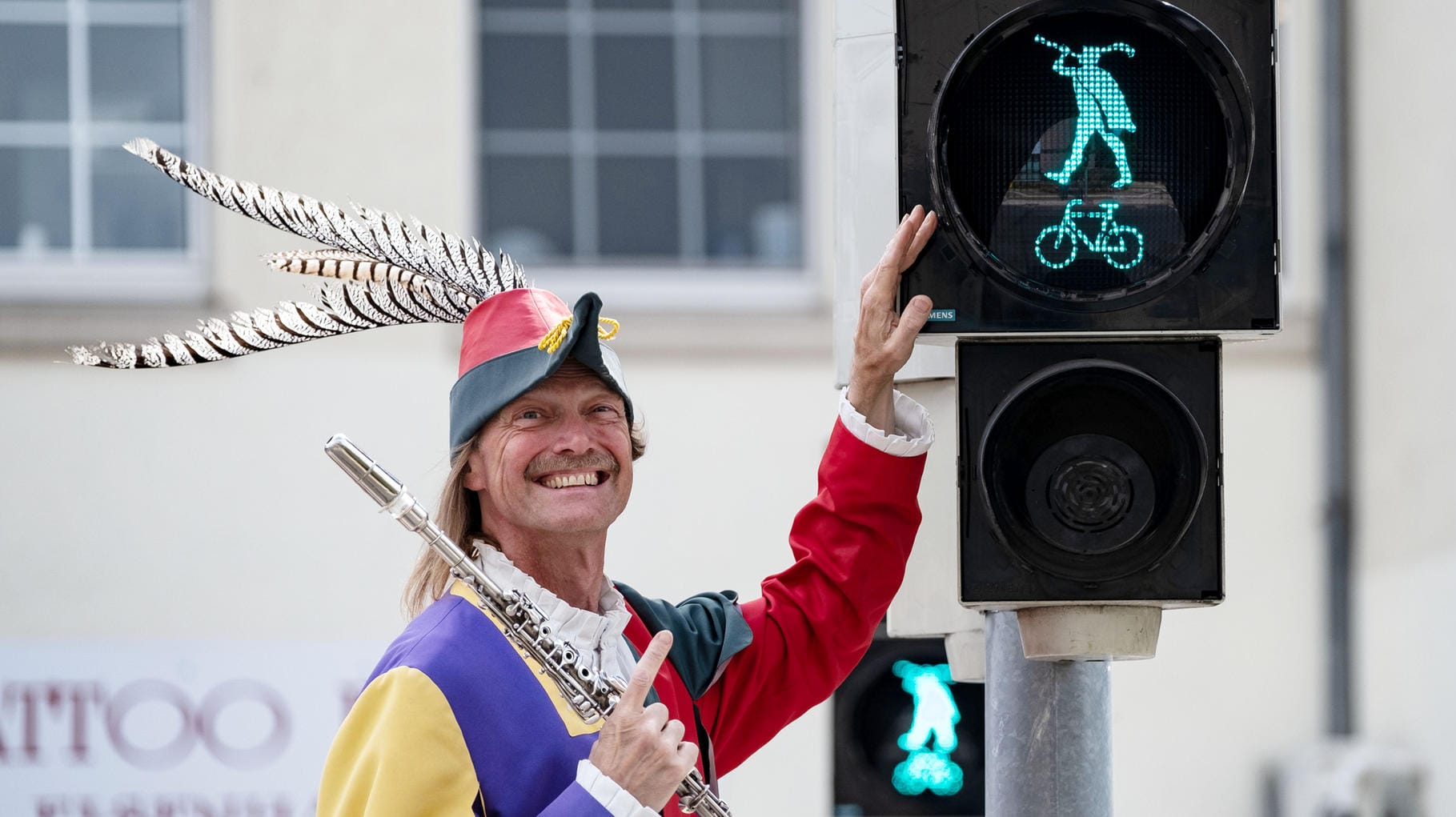 Der Rattenfänger von Hameln, dargestellt von Michael Boyer lächelt neben der Rattenfänger-Ampel in Hameln: Am Kastanienwall in der Nähe des Rathauses regelt ab sofort die Sagenfigur den Verkehr.