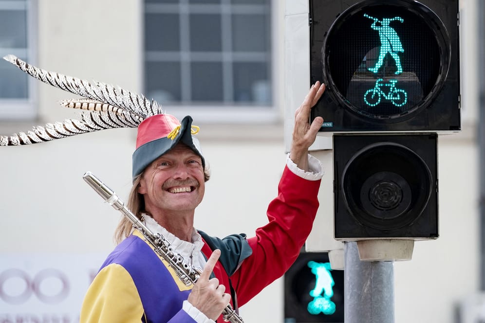 Der Rattenfänger von Hameln, dargestellt von Michael Boyer lächelt neben der Rattenfänger-Ampel in Hameln: Am Kastanienwall in der Nähe des Rathauses regelt ab sofort die Sagenfigur den Verkehr.