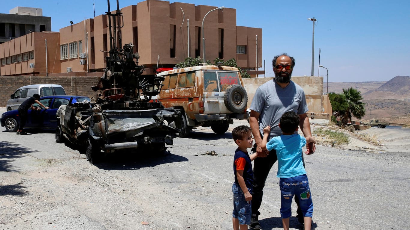 Eine Familie steht vor einem zerstörten Panzer in Tripolis: General Haftar hatte Anfang April eine Offensive auf Tripolis gestartet.
