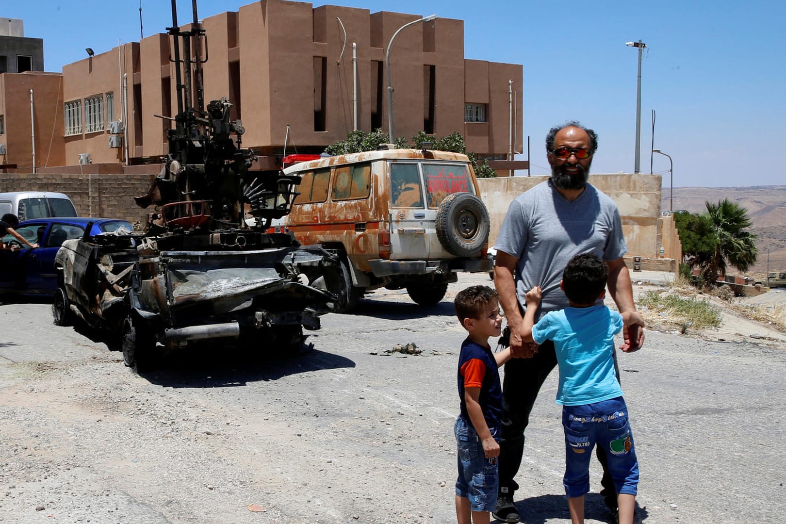 Eine Familie steht vor einem zerstörten Panzer in Tripolis: General Haftar hatte Anfang April eine Offensive auf Tripolis gestartet.