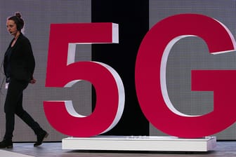 Eine Mitarbeiterin der Telekom geht an einem 5G Logo vorbei: Die Deutsche Telekom hat drei Wochen nach der Versteigerung der Frequenzen für die fünfte Mobilfunkgeneration sein 5G-Netz für Kunden geöffnet.