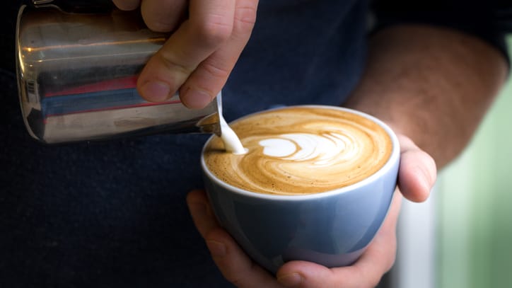 Barista bereitet einen Flat White zu: Charakteristisch für die Kaffeespezialität ist der feine Milchschaum.