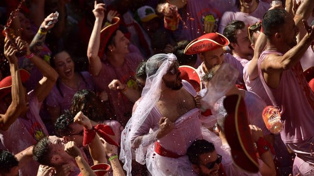 Weiß-Rot gekleidete Menschen feiern zu Beginn des "Sanfermines"-Festes, während sie auf das Abfeuern der Eröffnungsrakete "Chupinazo" warten. Weiß-Rot gekleidete Menschen feiern zu Beginn des "Sanfermines"-Festes, während sie auf das Abfeuern der Eröffnungsrakete "Chupinazo" warten.