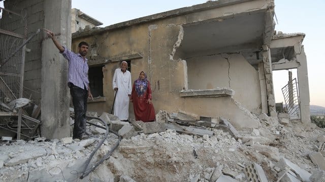 Bürger begutachten den Schaden an einem Haus, das bei Luftangriffen auf den Ort Muhambai zerstört wurde. Bürger begutachten den Schaden an einem Haus, das bei Luftangriffen auf den Ort Muhambai zerstört wurde.