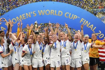 Carli Lloyd (M) hält den WM-Pokal inmitten der jubelnden US-Spielerinnen.