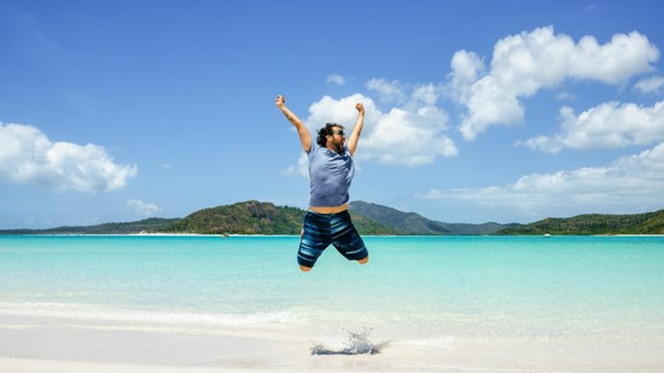Mann springt am Strand in die Luft: Für ungetrübte Urlaubsfreude lohnt es sich, die rechtlichen Regelungen genau zu kennen. (Symbolbild)