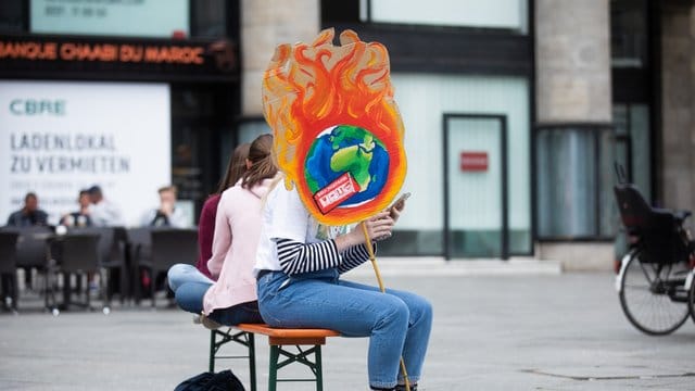 Eine Schülerin mit einem selbstgemachten Plakat vor dem Kölner Hauptbahnhof.