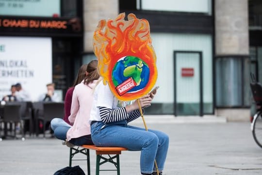 Eine Schülerin mit einem selbstgemachten Plakat vor dem Kölner Hauptbahnhof.