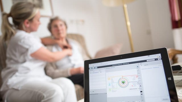 Eine Pflegerin legt einer Bewohnerin im Rahmen einer elektronischen Visite ein EKG-Gerät an, dass die Daten an einen Tablet-Computer und von dort aus zum Arzt überträgt. Eine Pflegerin legt einer Bewohnerin im Rahmen einer elektronischen Visite ein EKG-Gerät an, dass die Daten an einen Tablet-Computer und von dort aus zum Arzt überträgt.