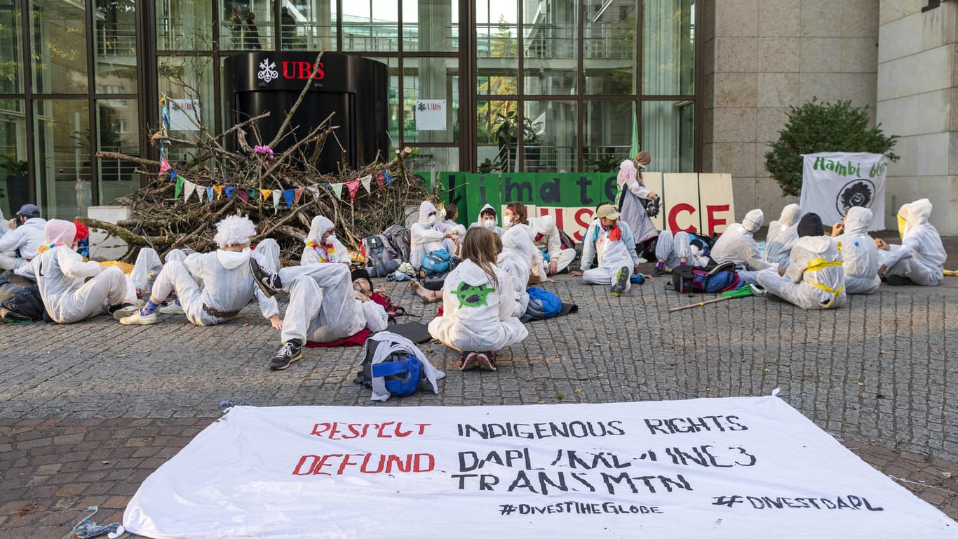 Basel: Aktivisten der Gruppe "Collective Climate Justice" blockieren mit Ästen den Eingang von dem UBS-Hauptsitz am Aeschenplatz und setzen beziehungsweise legen sich vor das Gebäude.
