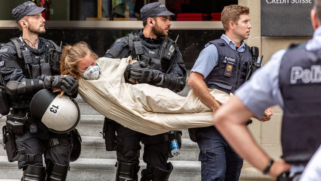 Polizisten nehmen eine Aktivistin nach der Blockade einer Bank in Zürich in Gewahrsam.