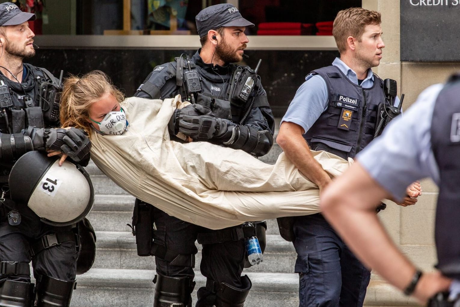 Polizisten nehmen eine Aktivistin nach der Blockade einer Bank in Zürich in Gewahrsam.