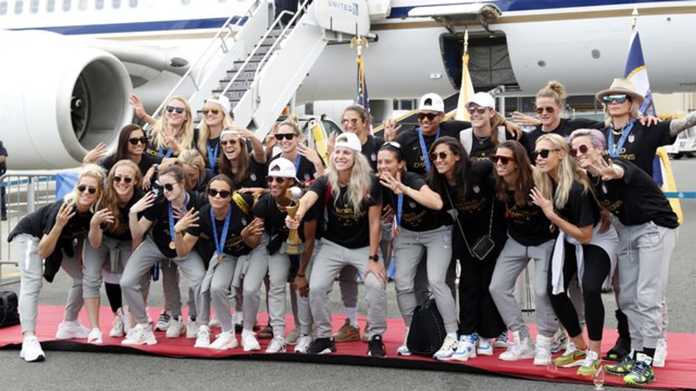 Die US-Fußballerinnen präsentieren bei der Ankunft in New York den WM-Pokal.