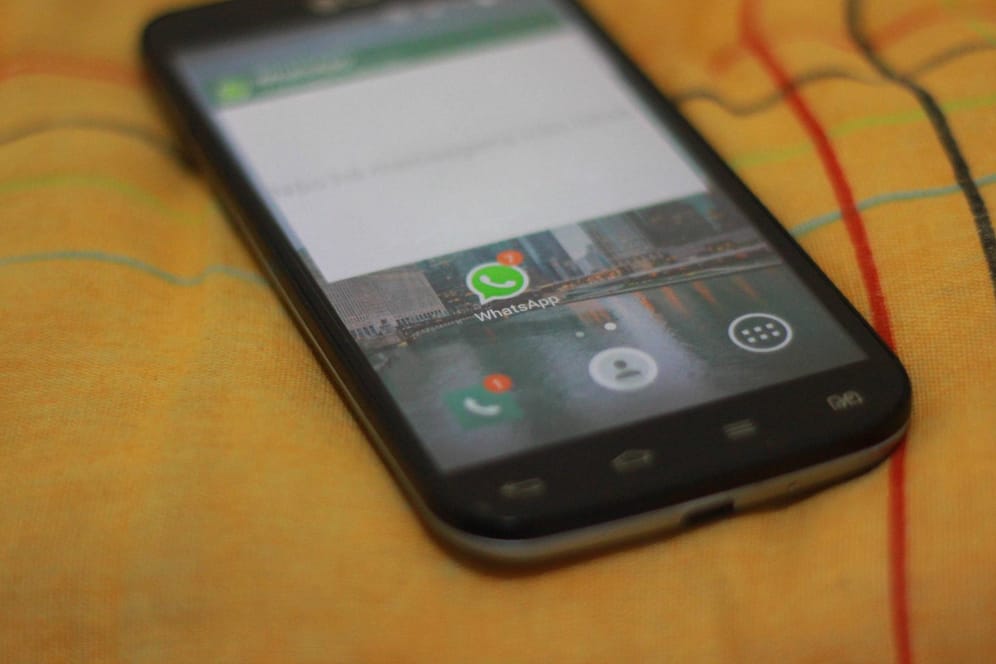 Ein Smartphone mit WhatsApp liegt auf einem Bett: Ein Kettenbrief droht Nutzern mit der Kontosperre.