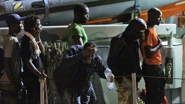 Migranten gehen von Bord eines italienischen Polizeiboots der Guardia di Finanza. Migranten gehen von Bord eines italienischen Polizeiboots der Guardia di Finanza.
