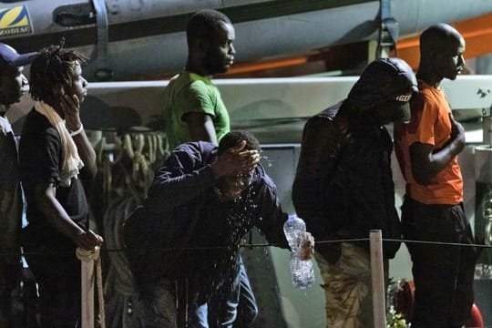 Migranten gehen von Bord eines italienischen Polizeiboots der Guardia di Finanza.