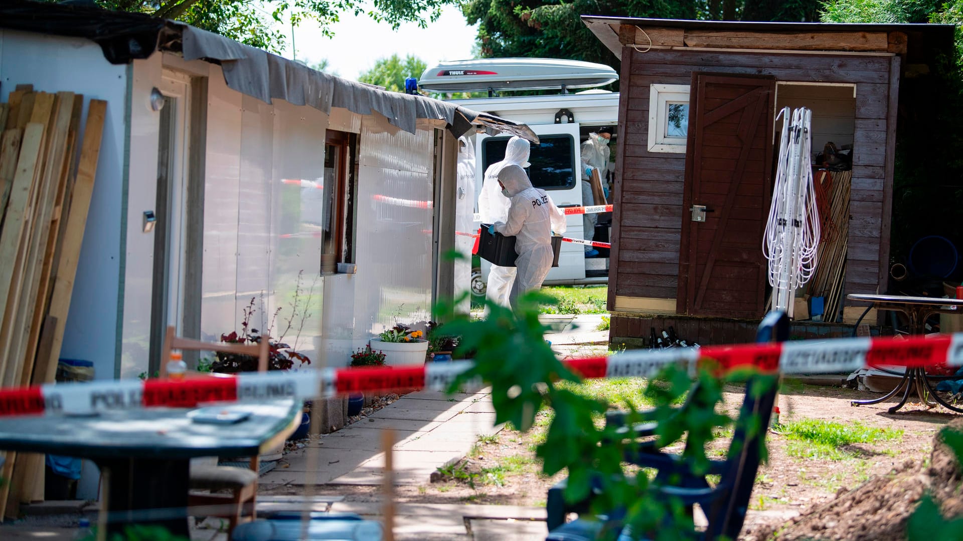 Bei den Durchsuchungen auf einer Parzelle auf dem Campingplatz in Lügde tragen Polizeibeamte der Kriminaltechnik eine Kiste in die Campinghütte eines neuen Tatverdächtigen.