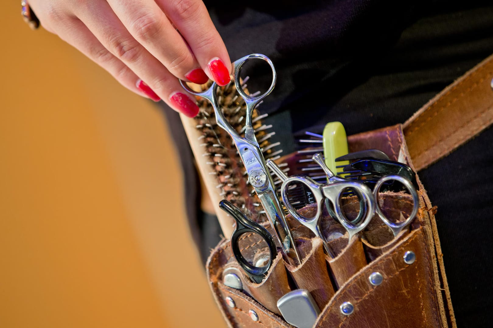 Das Handwerkszeug einer Friseurin in einer Gürteltasche: Friseure suchen händeringend Fachkräfte.