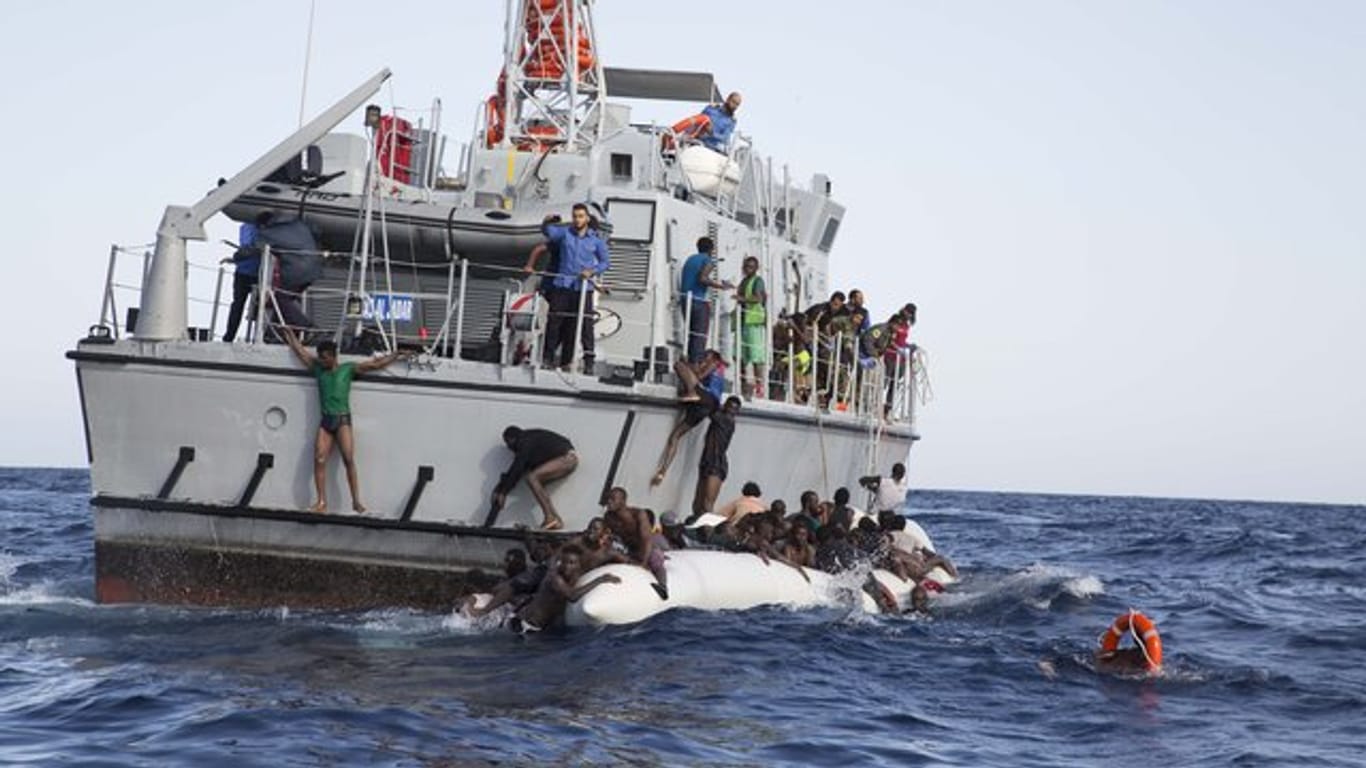 Libysche Flüchtlinge versuchen, an Bord eines Schiffs der libyschen Küstenwache zu gelangen.