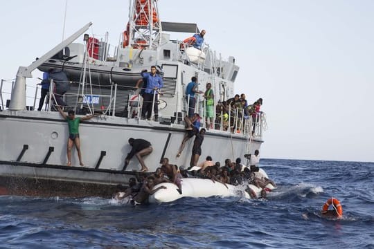 Libysche Flüchtlinge versuchen, an Bord eines Schiffs der libyschen Küstenwache zu gelangen.