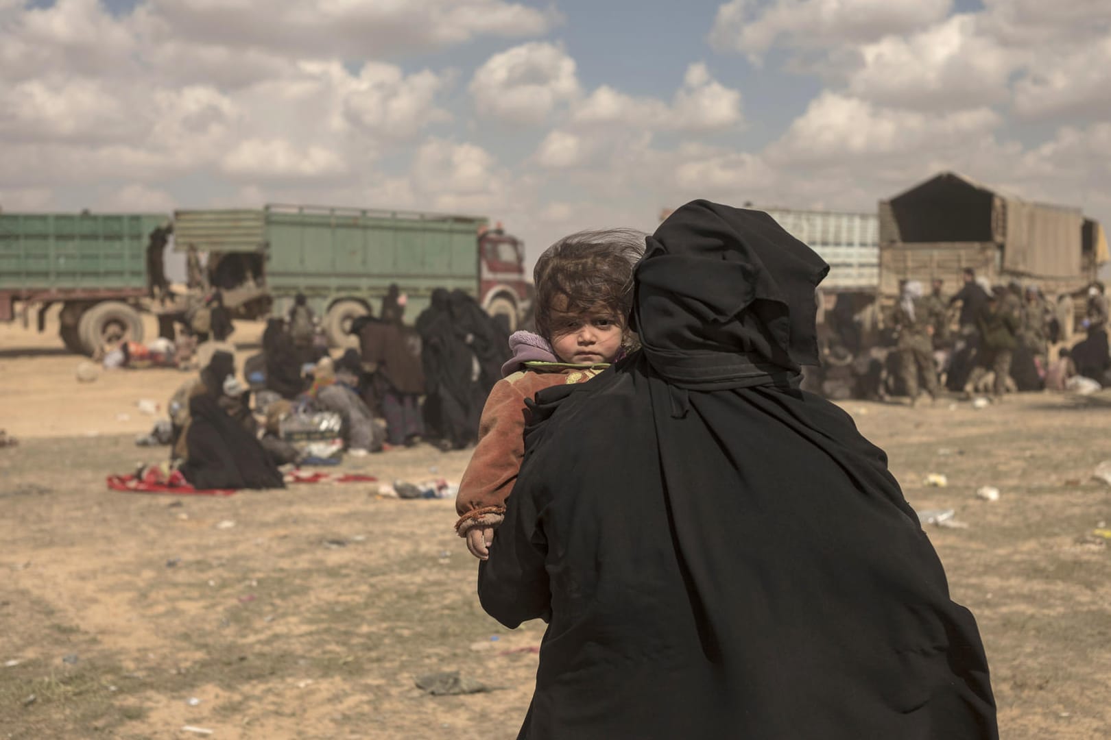 Eine Frau trägt ihr Kind durch ein Lager im syrischen Baghus