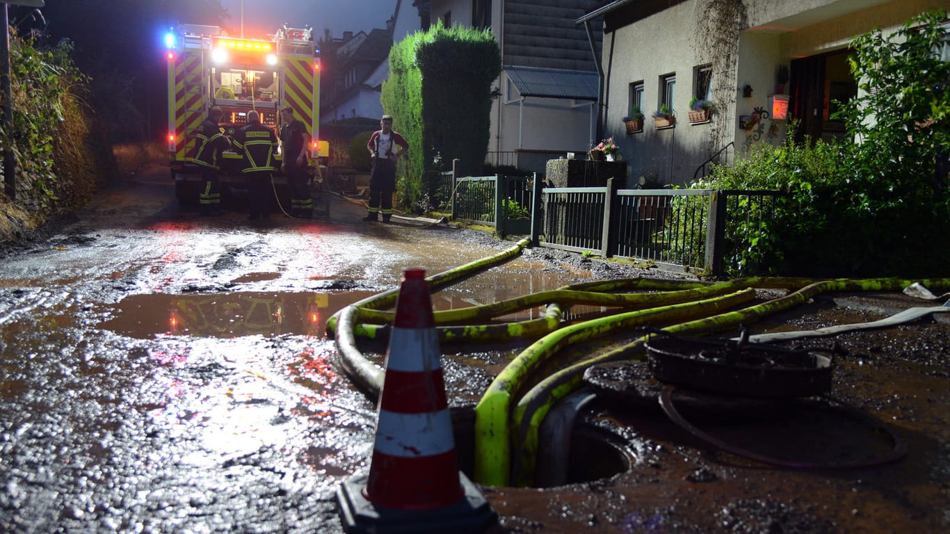 Feuerwehrleute pumpen einen Keller im Stadtteil Olewig leer: Ein heftiges Unwetter mit starkregen und Hagel war über die Region hinweggefegt und flutete zahlreiche Straßen und Keller.