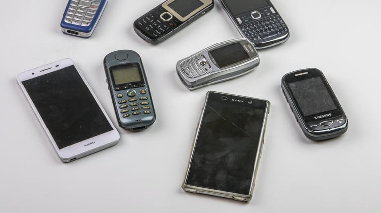 Alte Handys und Smartphones liegen auf einem Tisch: Ausgemusterte Modelle kann man an wohltätige Organisationen spenden.