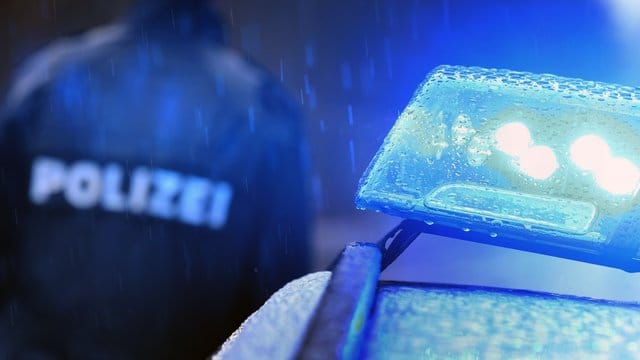 Ein Polizist im Regen vor einem Streifenwagen: Ersten Hinweisen zufolge lebte der getötete Mann in einem Obdachlosenlager. (Symbolbild)