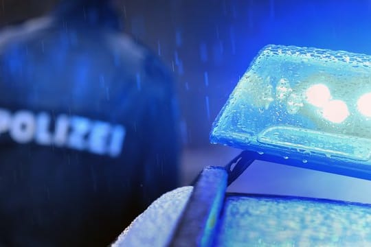 Ein Polizist im Regen vor einem Streifenwagen: Ersten Hinweisen zufolge lebte der getötete Mann in einem Obdachlosenlager. (Symbolbild)