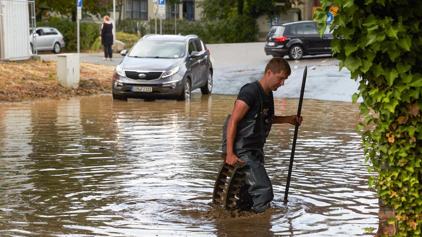 Überschwemmung in Boppard im Rheintal: Ein Feuerwehrmann sucht nach einem Starkregen in einer überfluteten Bahnüberführung nach dem Ablauf.