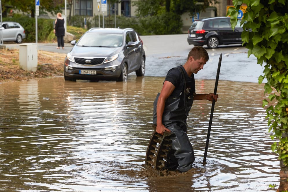 Überschwemmung in Boppard im Rheintal: Ein Feuerwehrmann sucht nach einem Starkregen in einer überfluteten Bahnüberführung nach dem Ablauf.