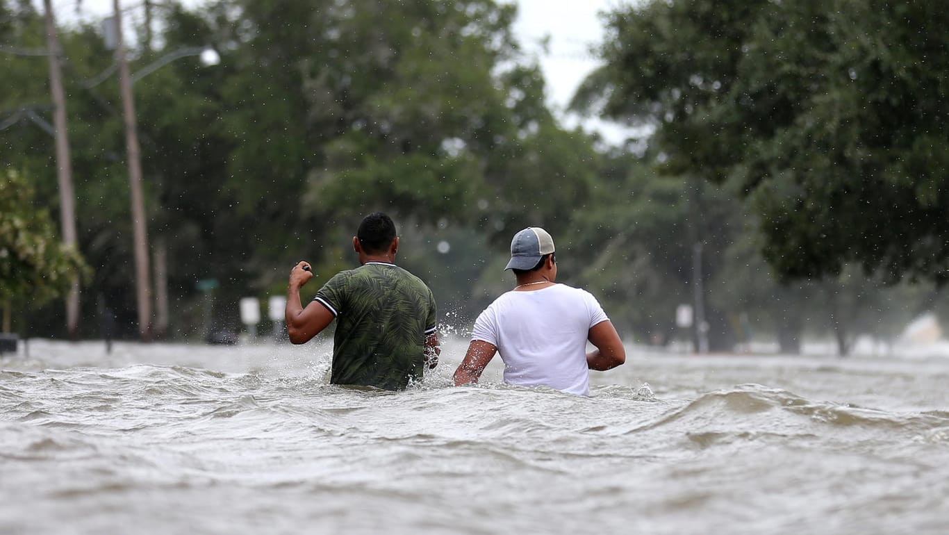 "Erste Auswirkungen von "Barry": Personen waten in Mandeville (US-Staat Louisiana) durch eine überschwemmte Straße.